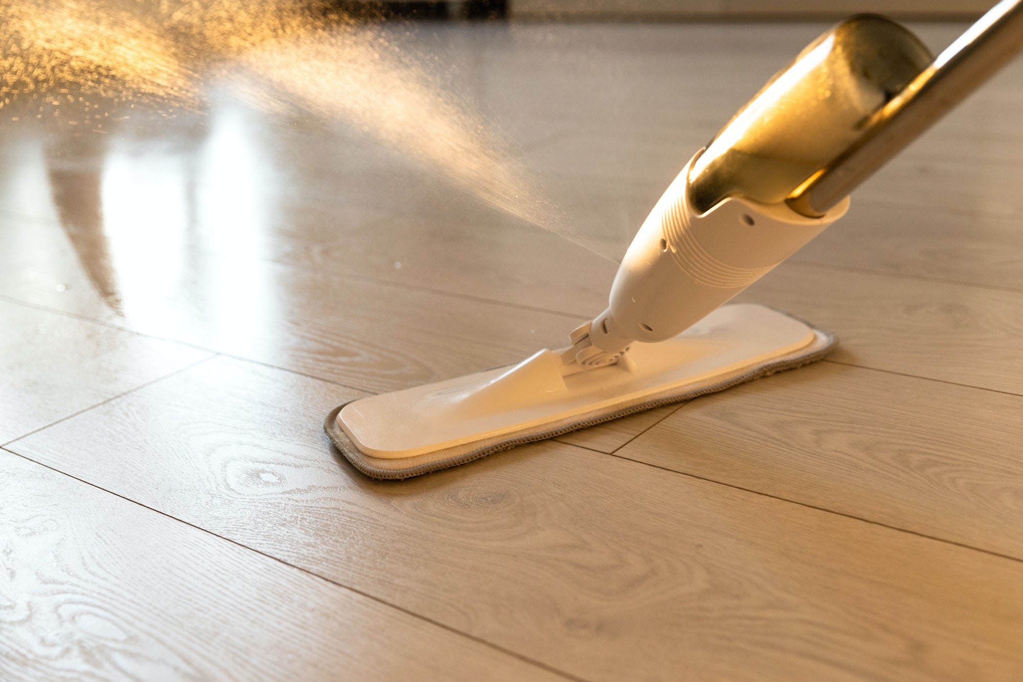 Person using spray mop pad and refillable bottle with cleaning solution, mopping the floor